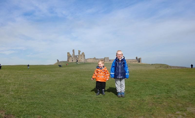 Two brothers standing in front of Dunstanburgh castle