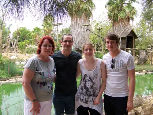 Mother, father, daughter and son posing in front of a monkey enclosure