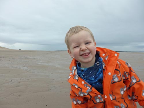 Toddler on Bamburgh Beach with a cheese smile