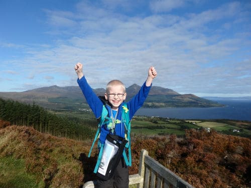 Child with arms up after climbing to top of a hill