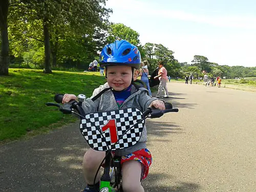 Toddler on a green bike smiling