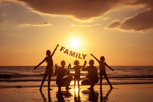 Happy family standing on the beach at the sunset time. They keep the letters forming the word " family". Concept of friendly family.