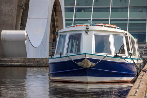 White and Blue boat moored near Falkirk Wheel, Scotland. The Falkirk Wheel is a rotating boat lift in Falkirk, Scotland, connecting the Forth and Clyde Canal with the Union Canal.