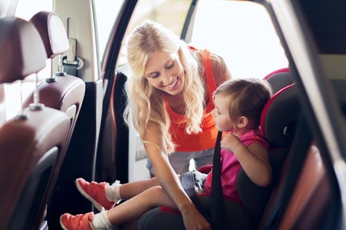 happy mother fastening child with car seat belt