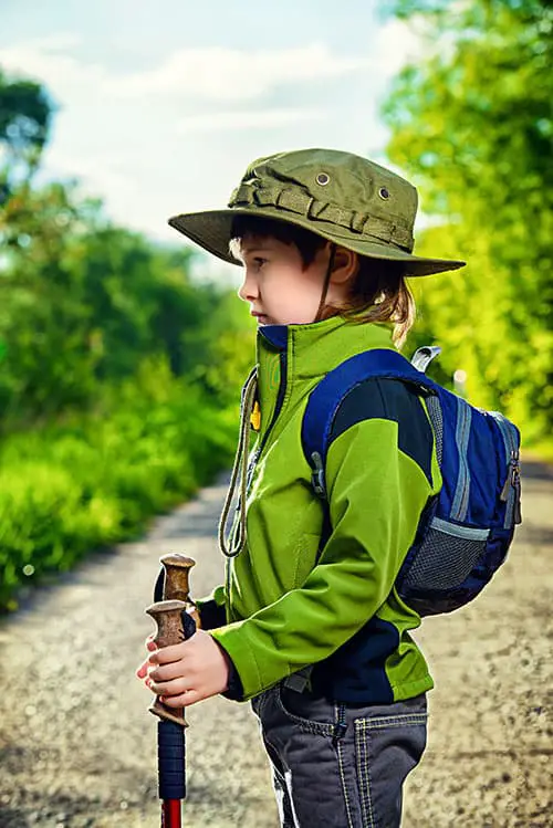 Portrait of a cute 7 years old boy in tourist clothes posing outdoor. Summer day.