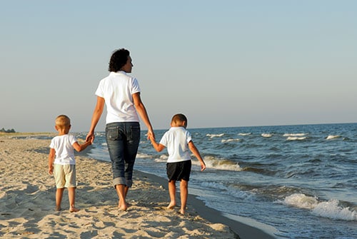 mum and two boys walking hand in hand along the beach