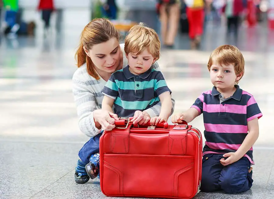 Happy family of three: Mother and two little sibling boys at the airport, traveling together.