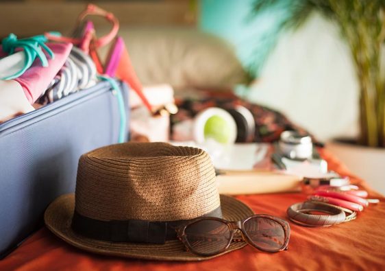 Woman's bedroom full of things ready to be taken on summer holiday.