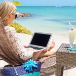 lady sitting on the beach with a laptop
