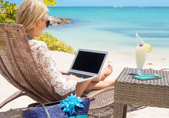 lady sitting on the beach with a laptop