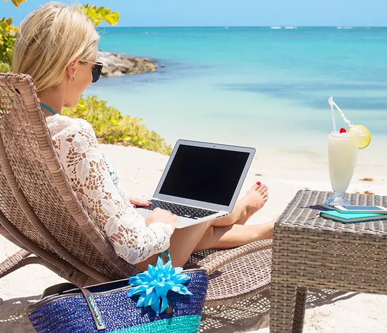 lady sitting on the beach with a laptop