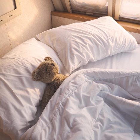 Brown teddy bear on bed at mobile car bedroom in the morning.
