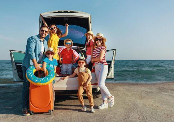 happy large family mother father and children in summer auto journey travel by car on beach