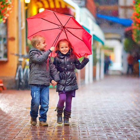happy kids walking under the rain on colourful street