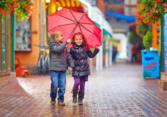 happy kids walking under the rain on colourful street