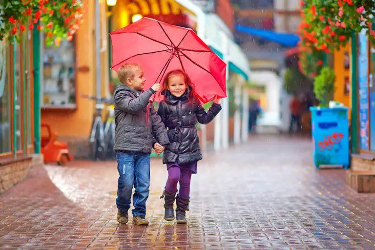 happy kids walking under the rain on colourful street