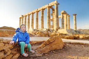 Cute young girl exploring the Ancient Greek temple of Poseidon at Cape Sounion, one of the major monuments of the Golden Age of Athens.