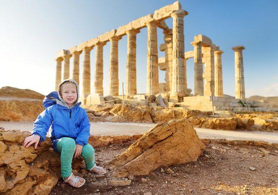 Cute young girl exploring the Ancient Greek temple of Poseidon at Cape Sounion, one of the major monuments of the Golden Age of Athens.